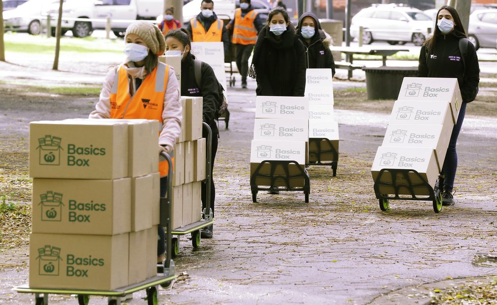 Очередь рабочих в масках доставляет заказанные правительством продукты питания в запертую жилую башню в Мельбурне