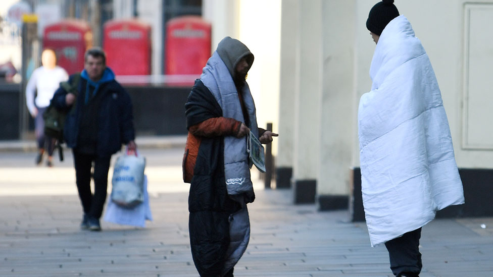 Бездомные люди стоят на тротуаре в час пик в центре Лондона, а в Лондоне, Великобритания, продолжается распространение коронавирусной болезни (COVID-19)