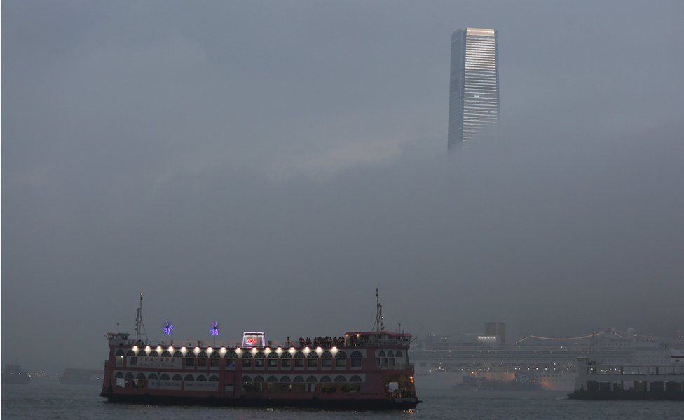 Паром в гавани Гонконга плывет перед зданием ICC в туманную погоду 9 марта 2016 г.