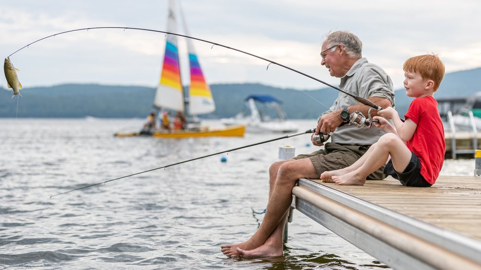 Idoso e neto pescando em lago no Quebec