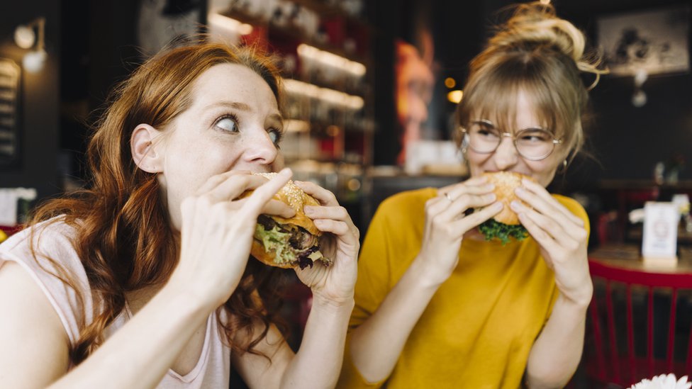 Mulheres comendo hambúrguer