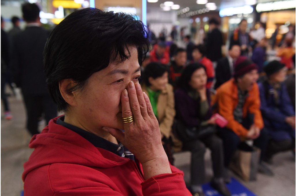 A woman who opposes South Korean President Moon Jae-in watches news footage of Moon and North Korean leader Kim Jong Un meeting in the Demilitarized Zone, at a railway station in Seoul on April 27, 2018. The leader of nuclear-armed North Korea Kim Jong Un and the South"s President Moon Jae-in said they were committed to the denuclearisation of the Korean peninsula after a historic summit on April 27. / AFP PHOTO / GREG BAKERGREG BAKER/AFP/Getty Images
