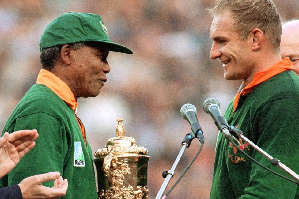 Presiden Afrika Selatan Nelson Mandela memberi selamat kepada kapten tim rugby Afrika Selatan Franois Pienaar sebelum menyerahkan trofi William Webb setelah kemenangan timnya atas Selandia Baru (15-12) di final Piala Dunia Rugbi di Ellis Park di Johannesburg 24 Juni 1995