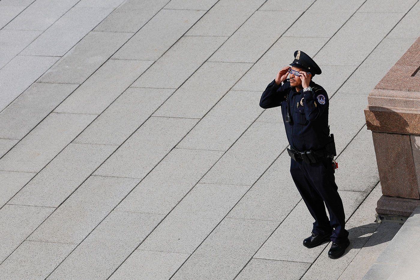A US Capitol police officer uses eclipse viewing glasses to look up at the partial solar eclipse in Washington DC - 8 April 2024 (Anna Moneymaker/Getty Images)