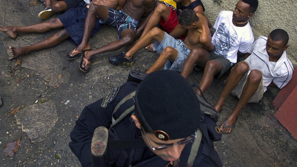 Un grupo de hombres siendo detenidos por un policía.