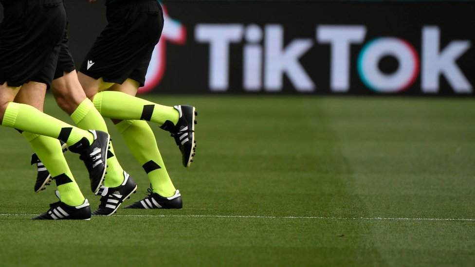 Piernas de futbolistas y el logo de TikTok