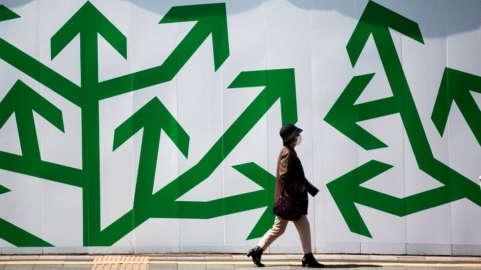 Después de años de deflación la deuda de Japón ha aumentado más de 200% del PIB. A pedestrian walks past decorated panelling used to shroud a construction site along a street in Tokyo