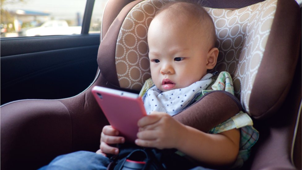 Beba drži telefon u auto sedištu