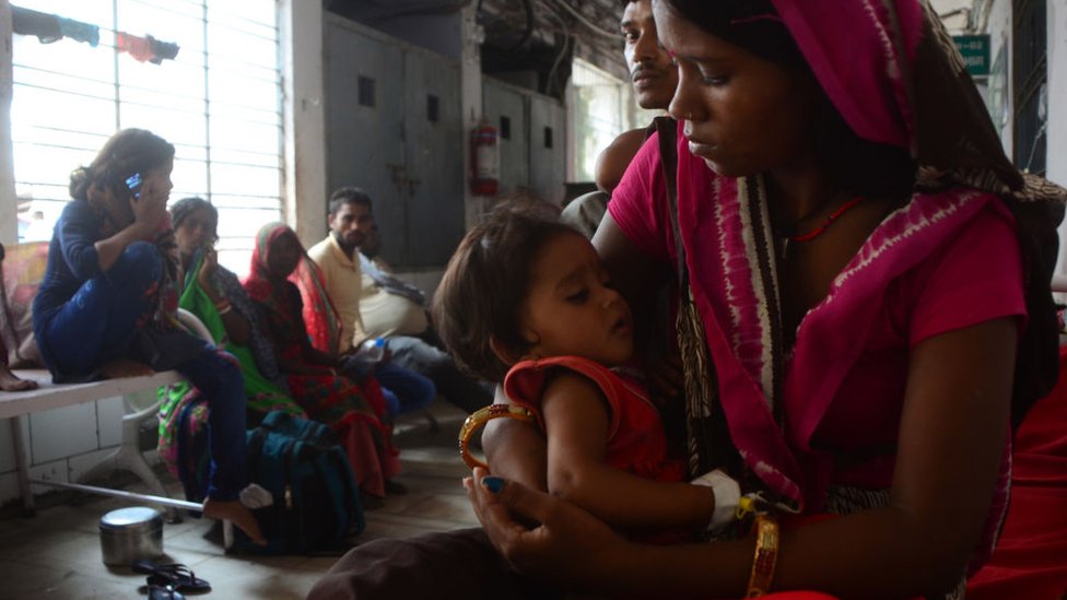 Индийский ребенок, страдающий AES (синдромом острого энцефалита), проходит лечение вне отделения интенсивной терапии, поскольку тележка для мусора проезжает через пациентов в SKMCH (Медицинский колледж и больница Шри Кришны) в Музаффарпуре 23 июня 2019 года.