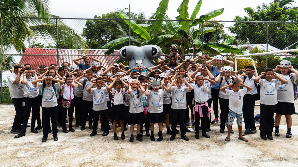 Niños con máscaras de tiburón y un tiburón inflable de juguete gigante