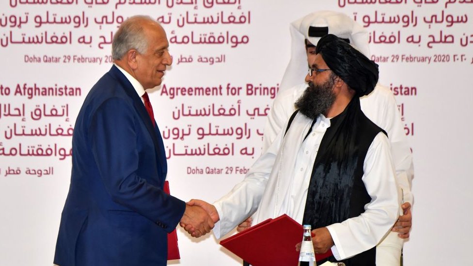El representante especial de EE.UU. para la reconciliación de Afganistán, Zalmay Khalilzad, y el cofundador del Talibán, Abdul Ghani Baradar, se dan la mano después de firmar un acuerdo de paz durante una ceremonia en la capital de Qatar, Doha, el 29 de febrero de 2020.