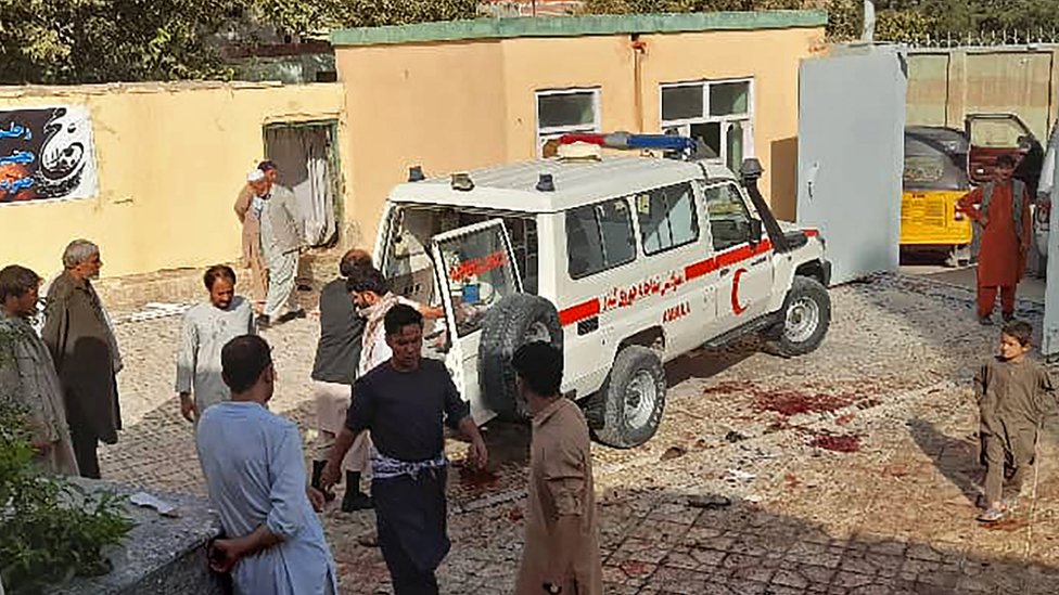 Afghan men stand next to an ambulance after a bomb attack at a mosque in Kunduz