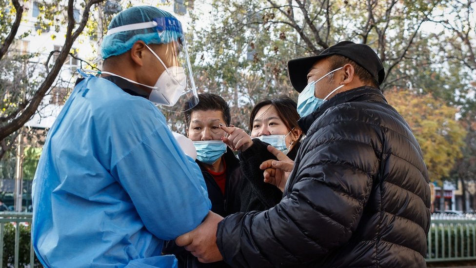 11月21日，一名婦女（右二) 在北京某處新冠測試點與一名志願衛生工作者（左）爭論