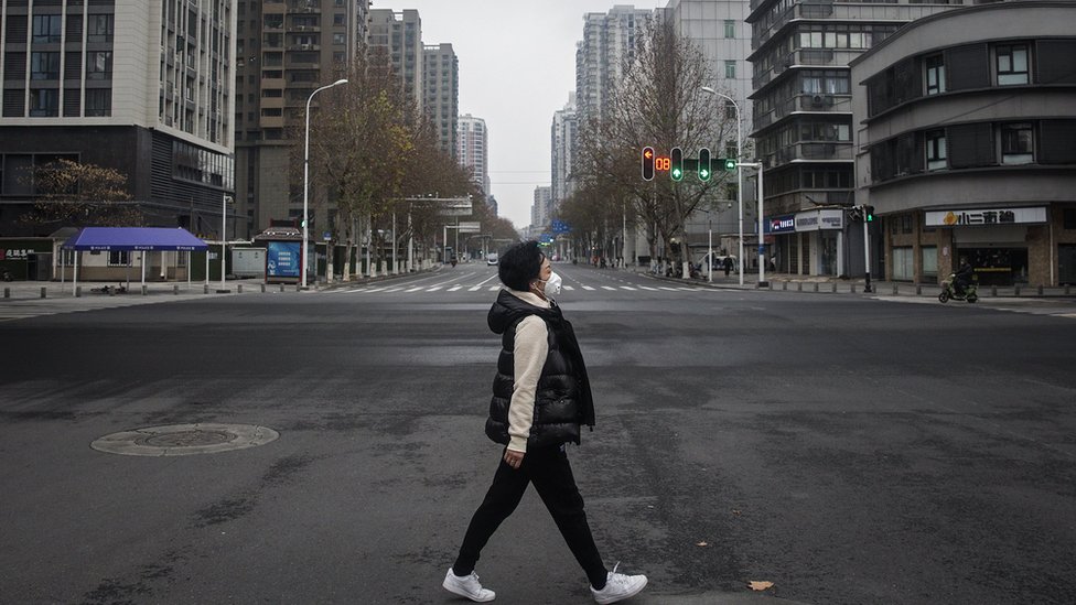 Женщина идет по пустой улице в Ухане, Китай