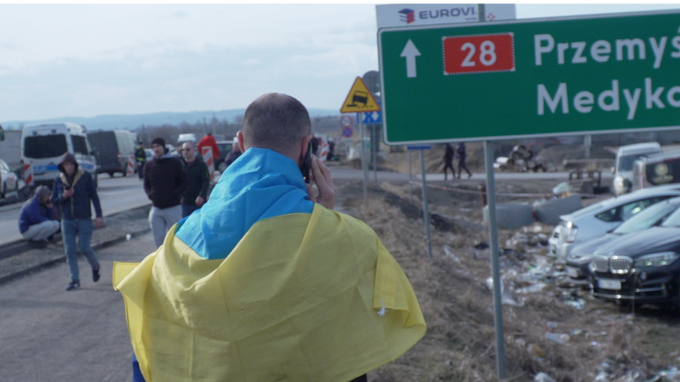 Muškarac telefonira ogrnut ukrajinskom zastavom