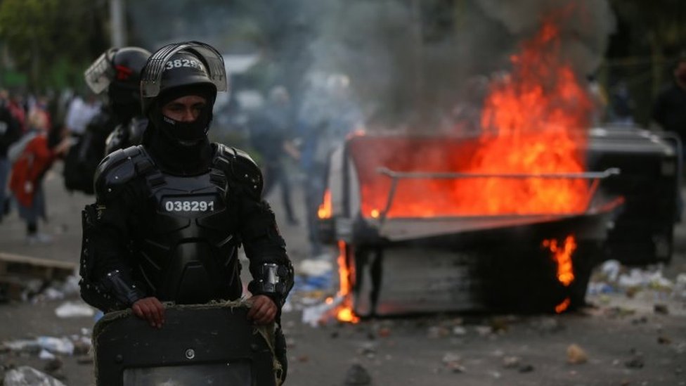 Riot police stand next to a burning garbage container during clashes with protesters after a man, who was detained for violating social distancing rules, died from being repeatedly shocked with a stun gun by officers, according to authorities, in Bogota, Colombia September 9, 2020.