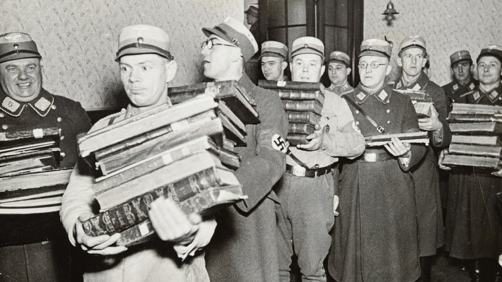 Oficiales nazis llevándose libros, presumiblemente para ser quemados