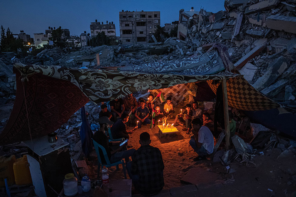 Niños palestinos se reúnen con velas durante un frágil alto el fuego en Beit Lahia, Gaza, el 25 de mayo de 2021, después de una protesta de los niños del vecindario contra los ataques en Gaza.