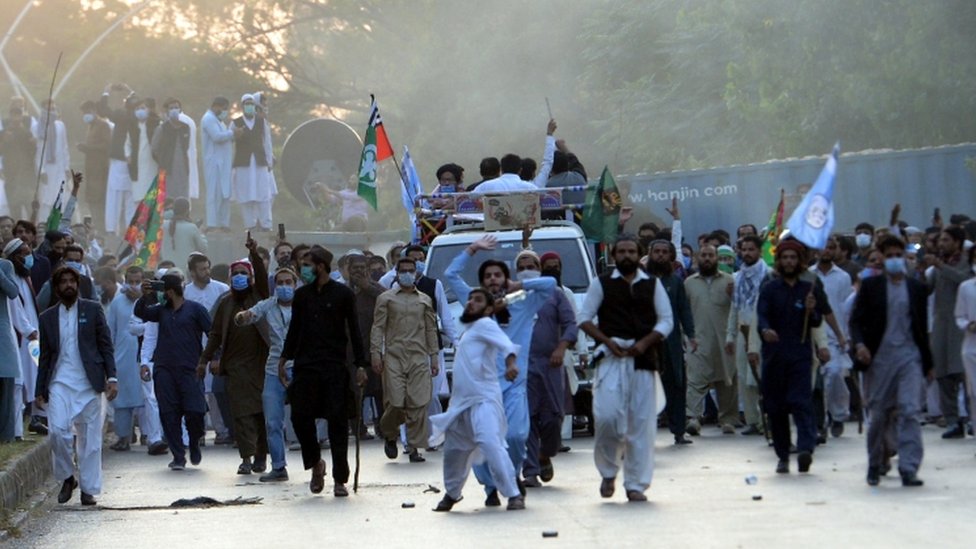 Protestors react after police fired tear gas shells to stop them reaching the French embassy in Islamabad