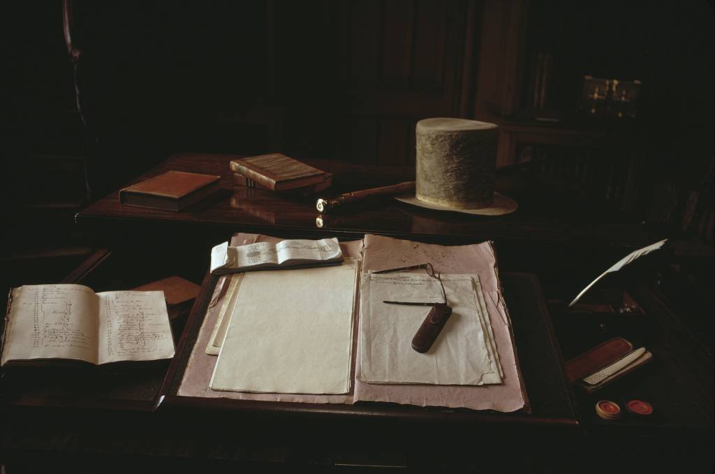Gafas, un sombrero, una pluma y papel de escribir sobre el escritorio en la casa del novelista, dramaturgo y poeta escocés