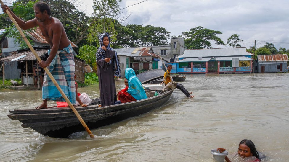 Люди катаются на лодке в затопленном районе после сильных муссонных дождей в Дохраре недалеко от Дакки, Бангладеш