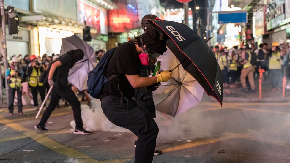 Протестующие, выступающие за демократию, реагируют на слезоточивый газ полиции во время демонстрации 20 октября 2019 года в Гонконге, Китай