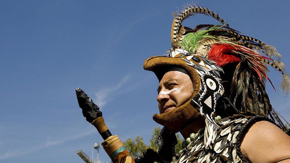 Un hombre representa un guerrero azteca