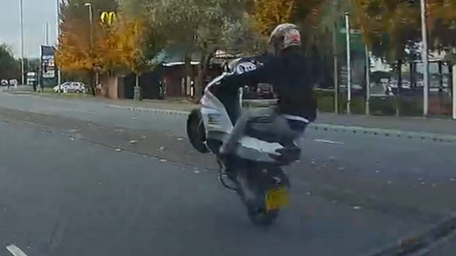 A moped rider performs a wheelie in Newport