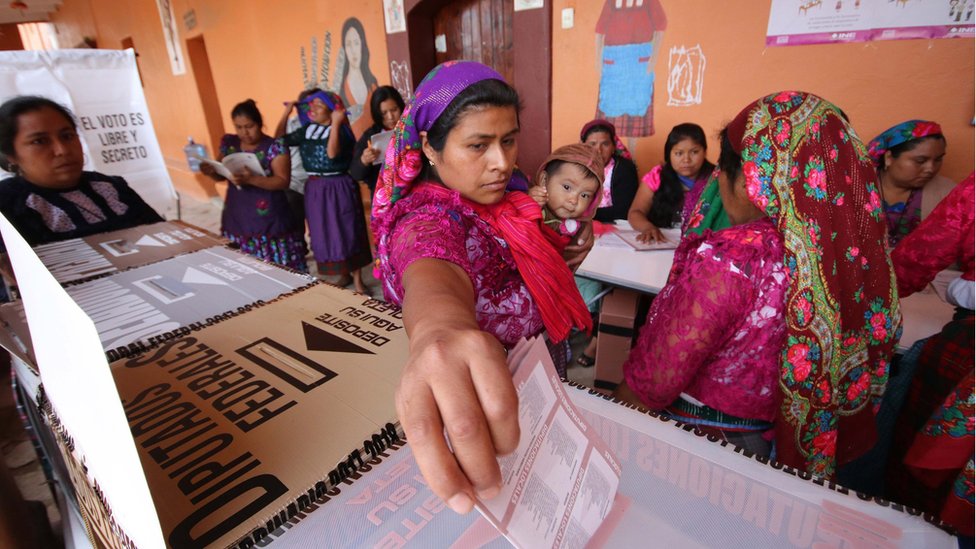 Женщина с младенцем опускает свой бюллетень на избирательном участке во время президентских выборов в Сан-Бартоломе-Киалана, штат Оахака, Мексика, 1 июля 2018 г.