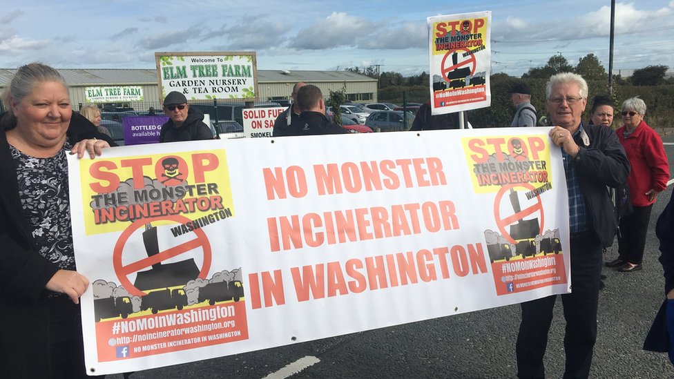 Протестующие против мусоросжигательного завода в Вашингтоне с плакатом
