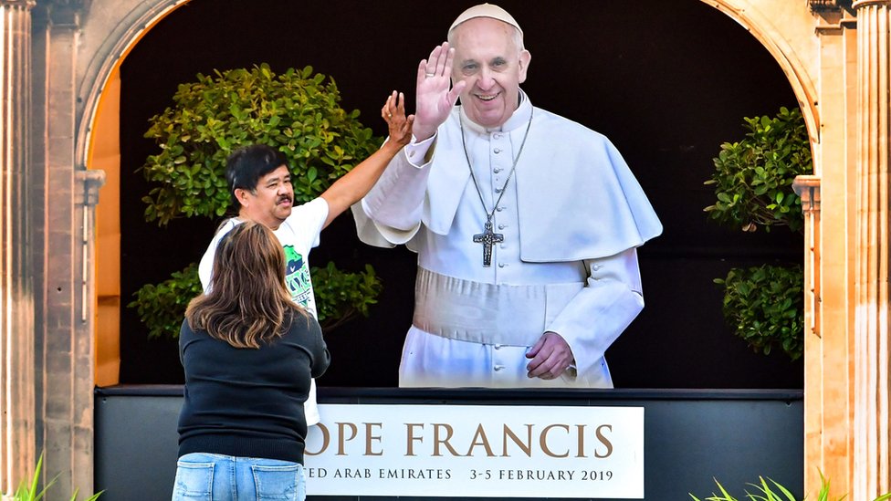 Papa'nın resmi önünde iki kişi