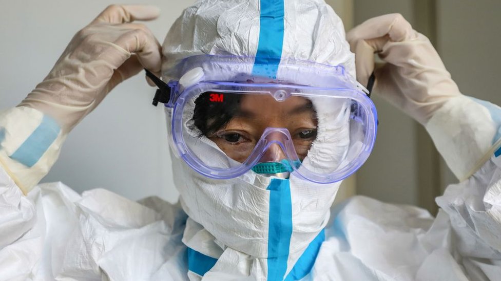 This photo taken on January 30, 2020 shows a doctor putting on a pair of protective glasses before entering the isolation ward at a hospital in Wuhan in China‘s central Hubei province