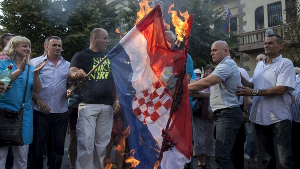 Лидер сербских националистов Воислав Шешель (C за флагом) и члены его партии сжигают хорватский национальный флаг, 5 августа