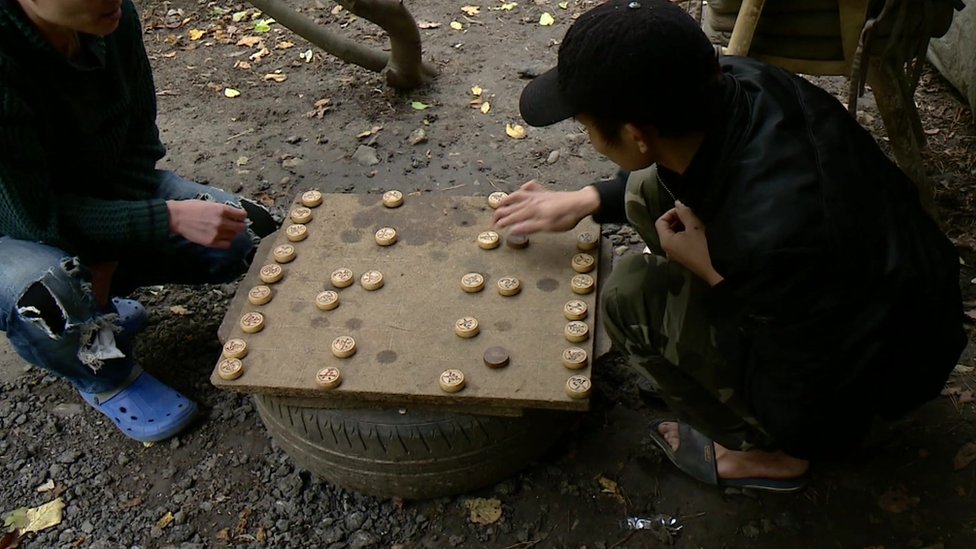 Двое мужчин играют в игру, ожидая в лагере