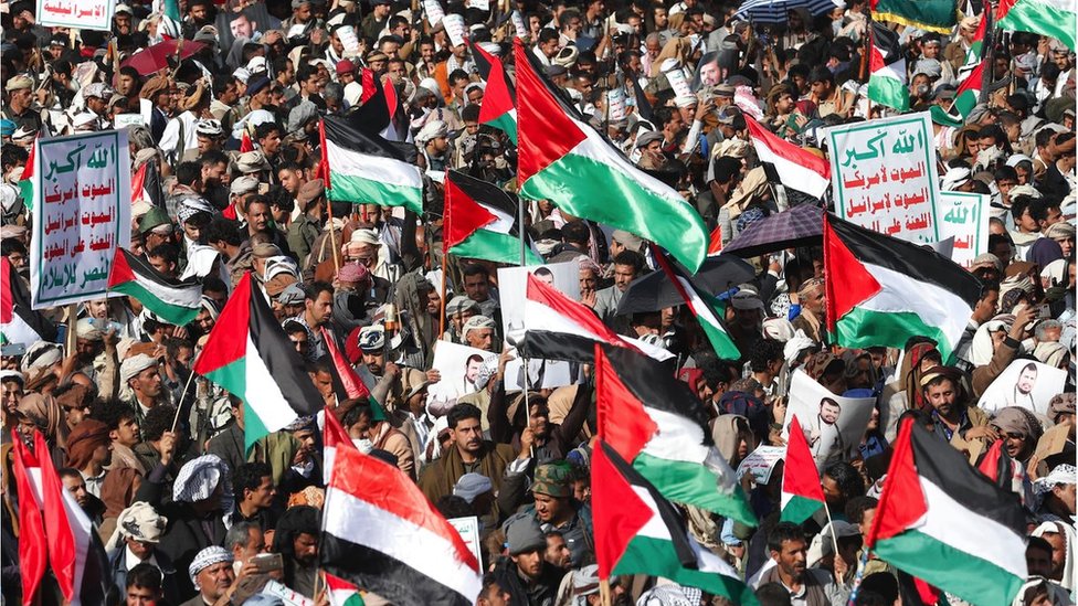 People wave Palestinian flags during a protest against a multinational operation to safeguard Red Sea shipping following US and UK airstrikes on Houthis military sites, in Sana'a, Yemen, 12 January 2024