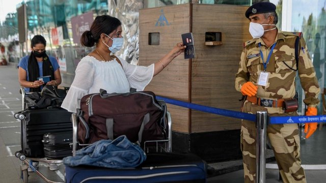 Una mujer le muestra el pasaporte a un guardia de seguridad en un aeropuerto