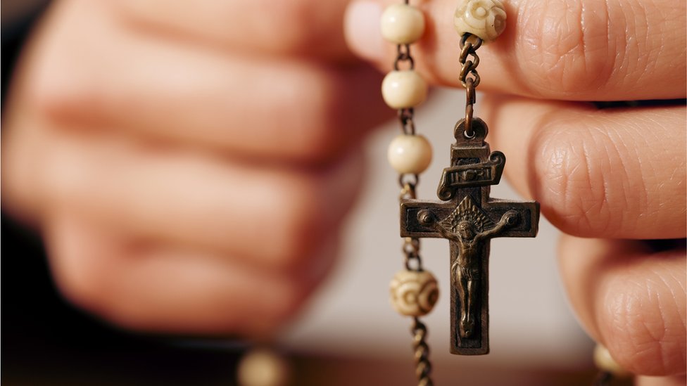 Manos sosteniendo un rosario con crucifijo