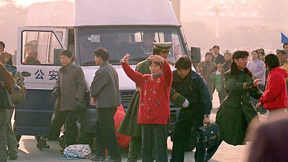 Protestors from the banned Falungong group are arrested by police 16 November 1999 in Beijing's Tiananmen Square as they raised a banned to appeal for help from visiting UN chief Kofi Annan. Up to fifty uniformed and plainclothes police officers pounced on the group as soon as they held up a bright red banner and started meditaition exercises. AFP PHOTO/Stephen SHAVER (Photo by STEPHEN SHAVER / AFP) (Photo by STEPHEN SHAVER/AFP via Getty Images)