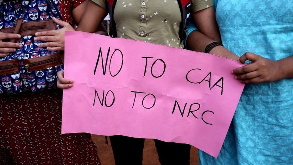 Индийские протестующие держат табличку с надписью «Нет CAA, нет NRC»