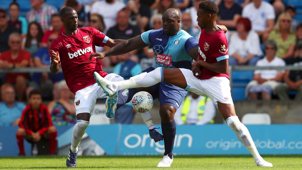 Adebayo Akinfenwa of Wycombe Wanderers battles for the ball with Reece Oxford (R) and Pedro Obiang of West Ham