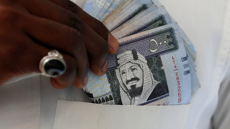 رجل يضع اوراق مالية سعودية في جيب جلبابه