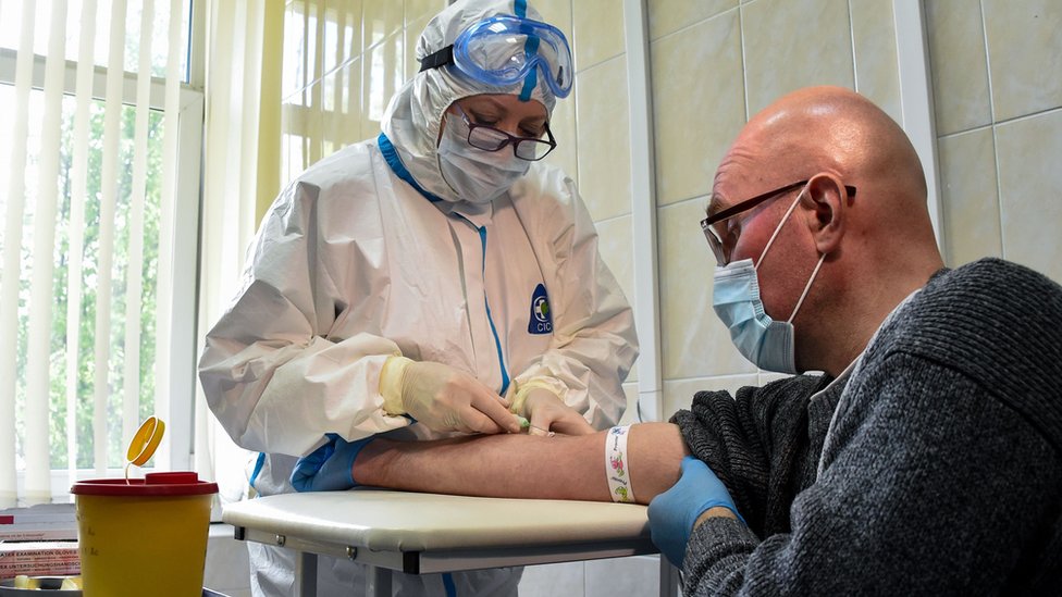 Медсестра в защитных костюмах берет кровь на анализ на антитела к COVID-19 в одной из поликлиник Москвы
