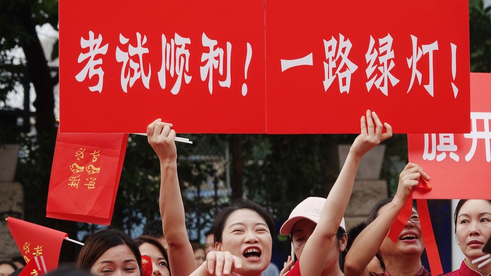 An examinee's mother holds a sign to wish her child good luck for the 2023 National College Entrance Exam (aka Gaokao) outside an exam venue on June 7, 2023 in Nanning, Guangxi Z