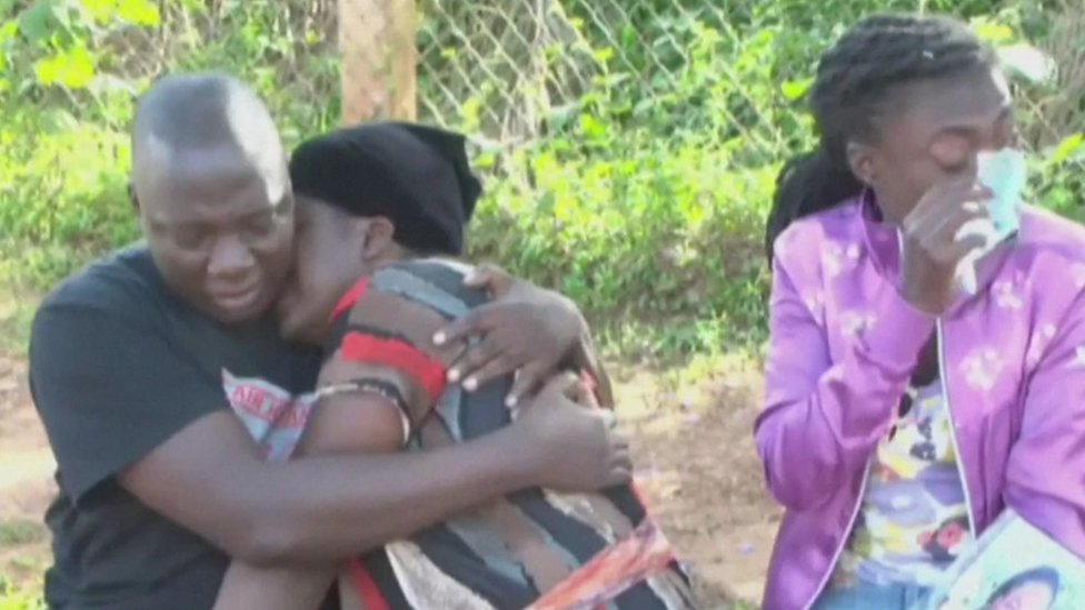 Three people weep following the news of a deadly crowd crush at a New Year event in Uganda