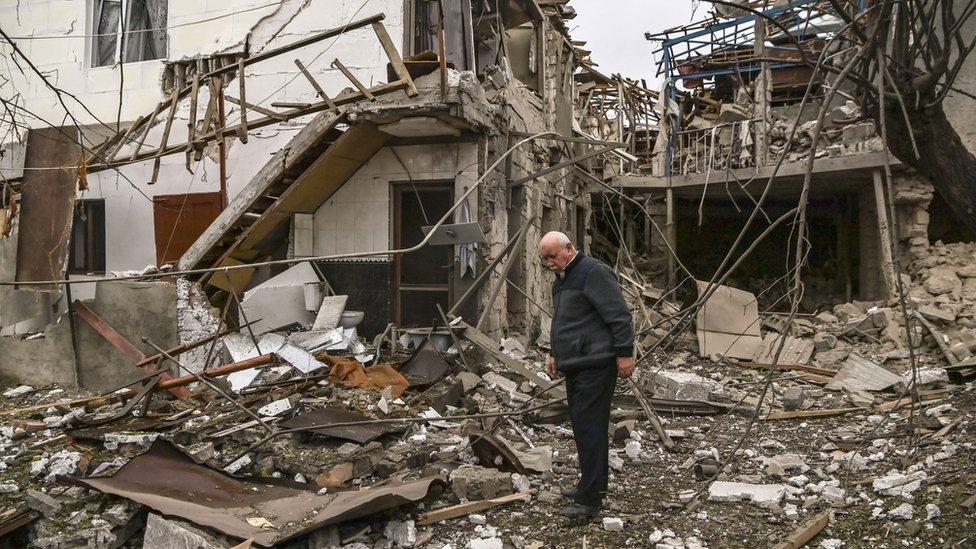 An elderly man stands in front of a destroyed house after shelling in the breakaway Nagorno-Karabakh region's main city of Stepanakert