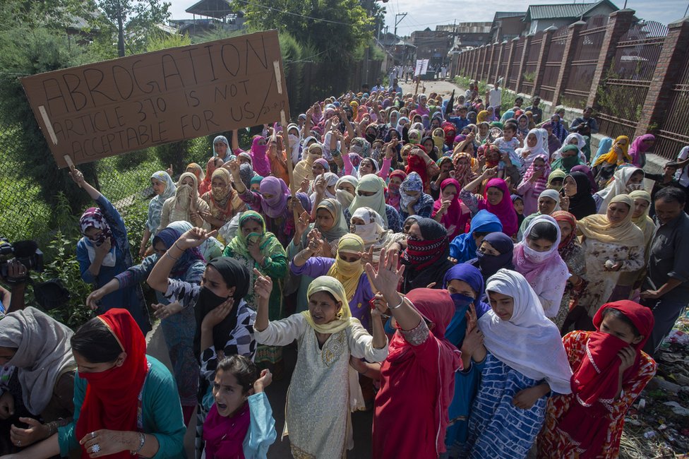 Протестующие в Шринагаре держат табличку с надписью: «Отмена статьи 370 для нас неприемлема»