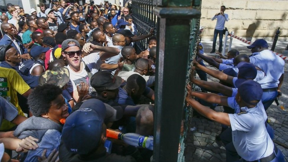 Южноафриканские студенты пробиваются через ворота парламента, когда полиция пытается им сопротивляться, во время жестоких столкновений с полицией на территории парламента, Кейптаун, Южная Африка, 21 октября 2015 г.