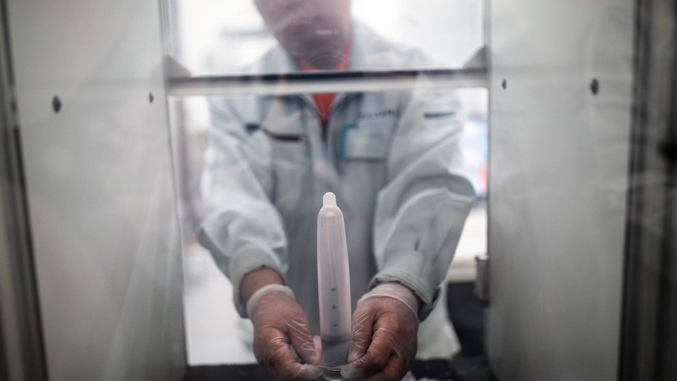 Un empleado del fabricante japonés de condones Sagami Rubber Industries pone un condón en una máquina para probar su resistencia llenándolo de aire.