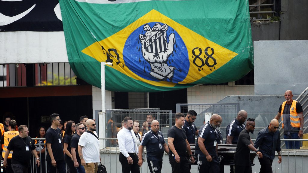 Pele's coffin is carried in front of a Brazilian flag