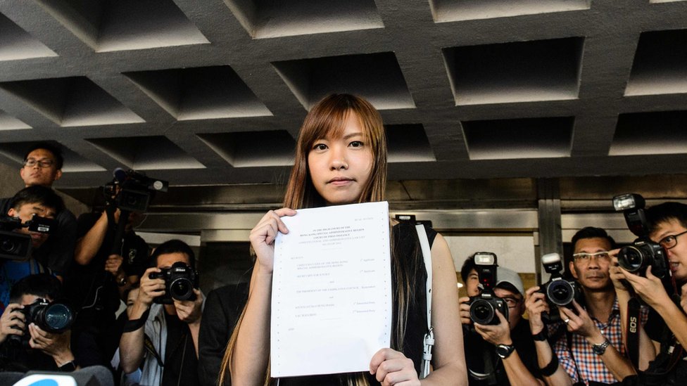 Законодатель, выступающий за независимость Яу Вай-цзин (C), держит решение суда, покидая Высокий суд Гонконга 15 ноября 2016 года.